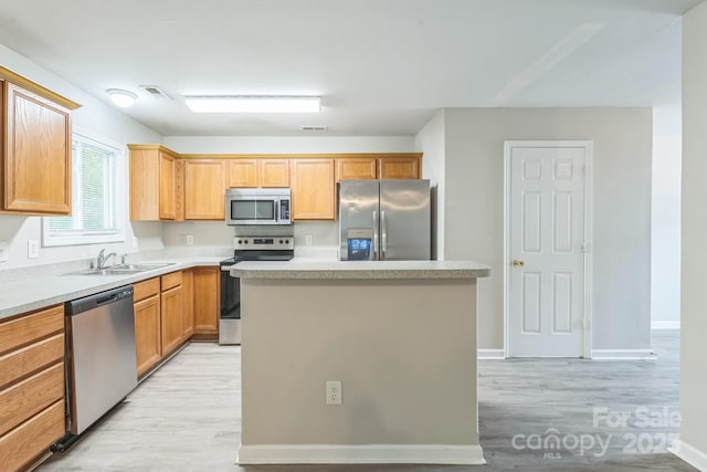13413 Golden Apple Ct, Charlotte, NC 28215 - kitchen featuring stainless steel appliances, a sink, light wood-style floors, and a kitchen island