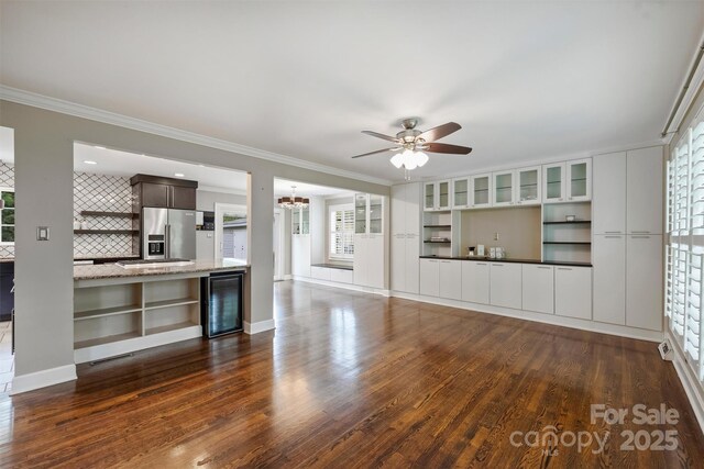 7050 Knightswood Dr, Charlotte, NC 28226 - unfurnished living room with beverage cooler, dark wood-style floors, a ceiling fan, healthy amount of natural light, and crown molding