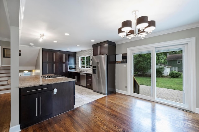 7050 Knightswood Dr, Charlotte, NC 28226 - kitchen with stainless steel appliances, a chandelier, crown molding, light wood-style floors, and dark brown cabinets