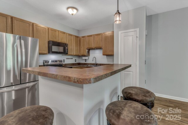 176 Brickton Village Cir Unit 302, Fletcher, NC 28732 - kitchen with appliances with stainless steel finishes, dark countertops, a sink, wood finished floors, and a breakfast bar area