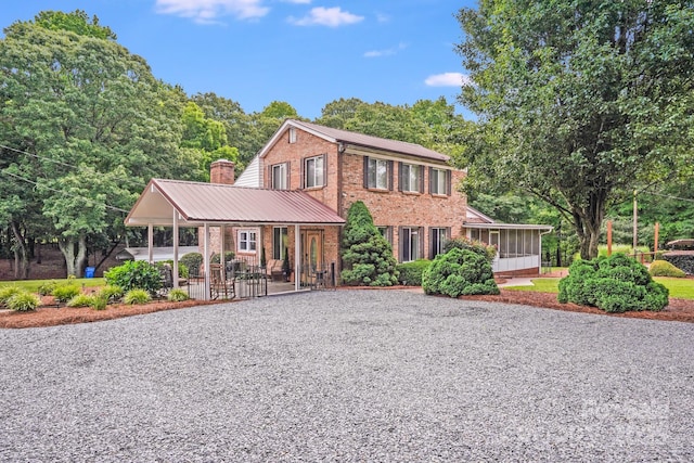 211 Drive Inn Rd, Locust, NC 28097 - view of front of property featuring brick siding, gravel driveway, a sunroom, a chimney, and a patio area