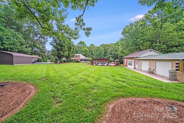 211 Drive Inn Rd, Locust, NC 28097 - view of green lawn featuring an outdoor structure, a patio, and a garage