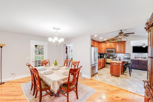 211 Drive Inn Rd, Locust, NC 28097 - dining area with a chandelier, a lit fireplace, baseboards, ceiling fan, and lofted ceiling