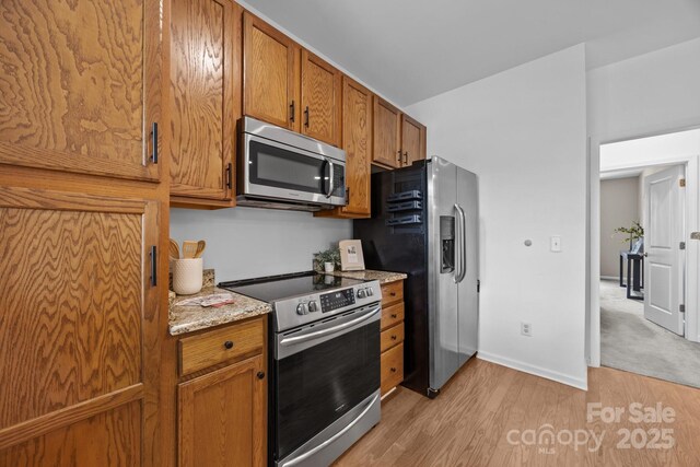1556 Walnut View Dr, Charlotte, NC 28208 - kitchen featuring stainless steel appliances, light wood-style floors, brown cabinetry, and light stone countertops