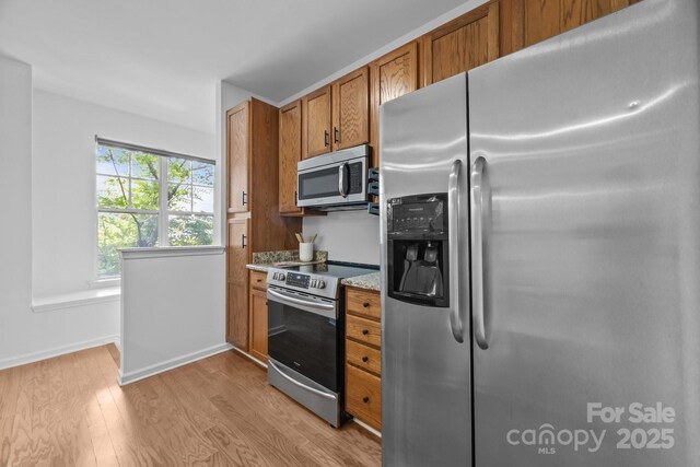 1556 Walnut View Dr, Charlotte, NC 28208 - kitchen with stainless steel appliances, light wood finished floors, brown cabinets, and light stone countertops