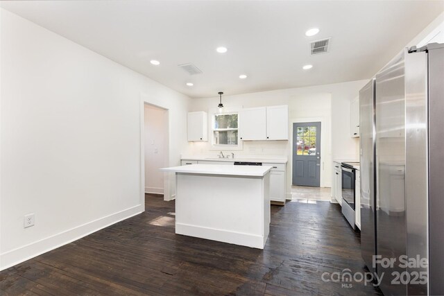 1112 Concord Ave, Monroe, NC 28110 - kitchen featuring appliances with stainless steel finishes, light countertops, a kitchen island, white cabinetry, and dark wood-style floors