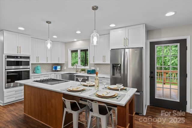 625 S Magnolia St, Mooresville, NC 28115 - kitchen with appliances with stainless steel finishes, decorative backsplash, white cabinetry, a sink, and hanging light fixtures