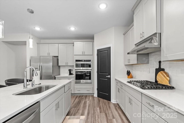 9009 Myrna Dr, Gastonia, NC 28056 - kitchen featuring appliances with stainless steel finishes, under cabinet range hood, light countertops, tasteful backsplash, and hanging light fixtures