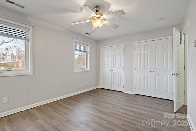31 English Ivy Rd, Asheville, NC 28806 - unfurnished bedroom with multiple closets, wood finished floors, baseboards, and ceiling fan