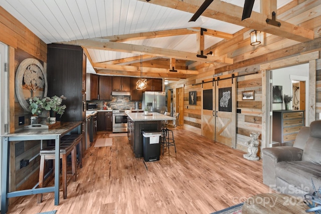72 Wakulla Dr, Maggie Valley, NC 28751 - kitchen featuring appliances with stainless steel finishes, a barn door, wooden walls, under cabinet range hood, and a breakfast bar