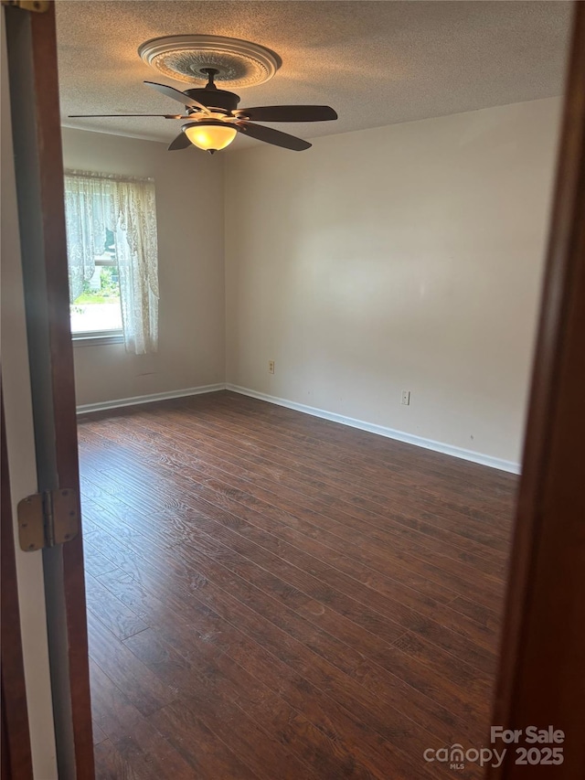 550 Camrose Cir NE, Concord, NC 28025 - empty room featuring a textured ceiling, dark wood-style flooring, a ceiling fan, and baseboards