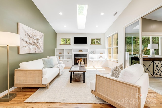506 Hiawassee Ave, Black Mountain, NC 28711 - living room featuring wood finished floors, vaulted ceiling, a glass covered fireplace, a skylight, and baseboards