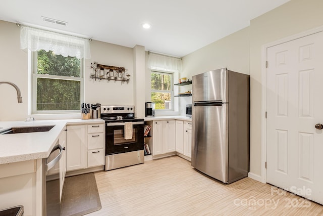 506 Hiawassee Ave, Black Mountain, NC 28711 - kitchen with stainless steel appliances, a sink, light wood finished floors, white cabinets, and recessed lighting