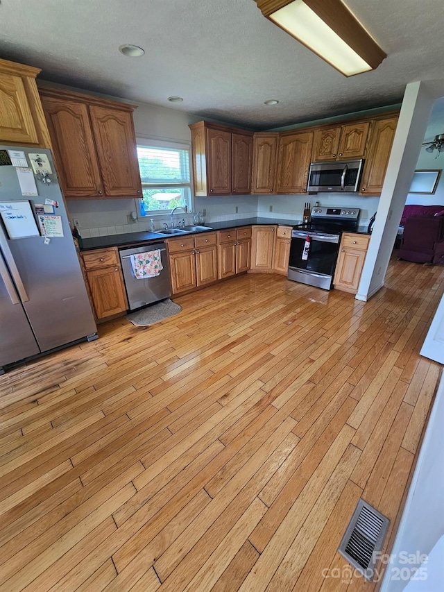 1670 Jamestown Rd, Morganton, NC 28655 - kitchen with appliances with stainless steel finishes, dark countertops, light wood finished floors, brown cabinets, and a textured ceiling
