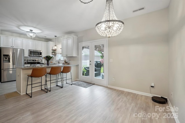 7931 Baylis Dr, Huntersville, NC 28078 - kitchen with stainless steel appliances, a peninsula, white cabinetry, light wood-style flooring, and french doors