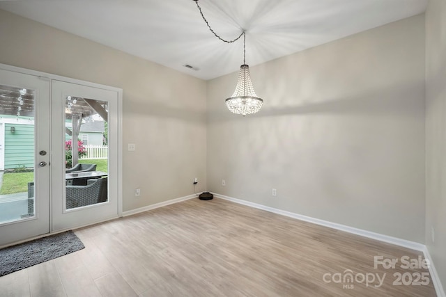 7931 Baylis Dr, Huntersville, NC 28078 - unfurnished dining area featuring wood finished floors, baseboards, a chandelier, and french doors