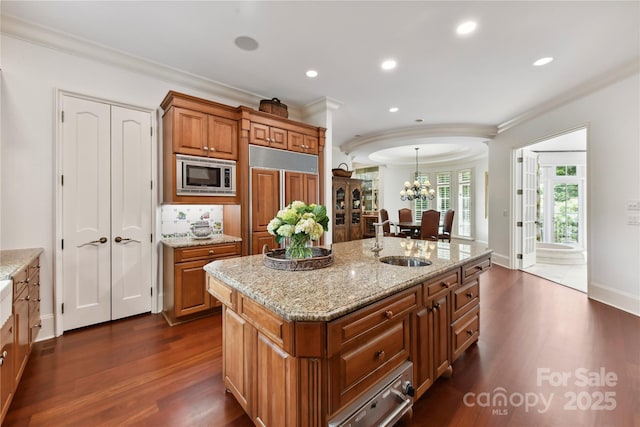 2240 La Maison Dr, Charlotte, NC 28226 - kitchen with built in appliances, a sink, crown molding, brown cabinetry, and a chandelier