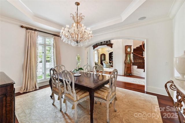 2240 La Maison Dr, Charlotte, NC 28226 - dining room with arched walkways, a chandelier, wood finished floors, a tray ceiling, and ornamental molding