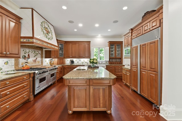 2240 La Maison Dr, Charlotte, NC 28226 - kitchen featuring built in appliances, brown cabinets, light stone countertops, dark wood-type flooring, and ornamental molding
