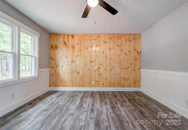 1010 Fallston Rd, Shelby, NC 28150 - spare room featuring wood finished floors, wood walls, plenty of natural light, baseboards, and a ceiling fan
