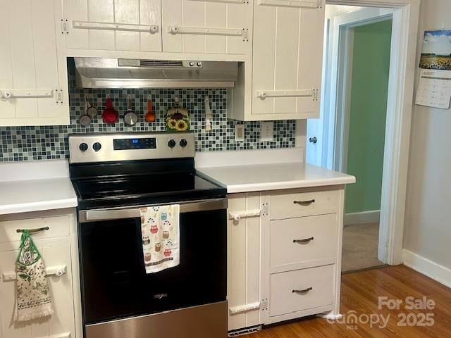 1014 Wright St SW Unit # 4, Lenoir, NC 28645 - kitchen with electric stove, under cabinet range hood, wood finished floors, tasteful backsplash, and white cabinetry