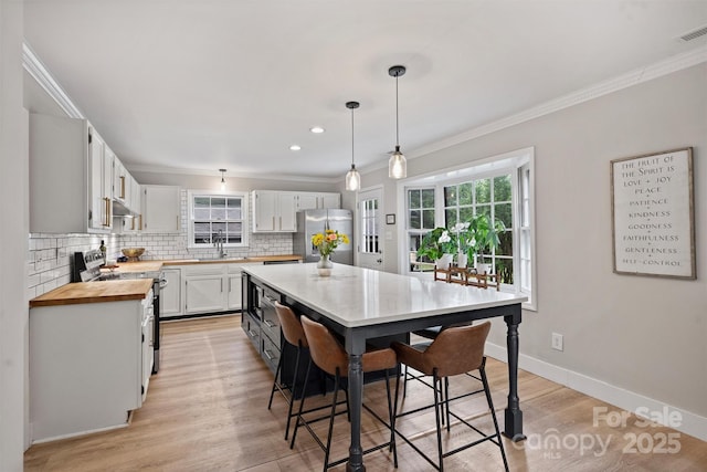1119 Thornsby Ln, Matthews, NC 28105 - kitchen featuring stove, freestanding refrigerator, under cabinet range hood, crown molding, and backsplash