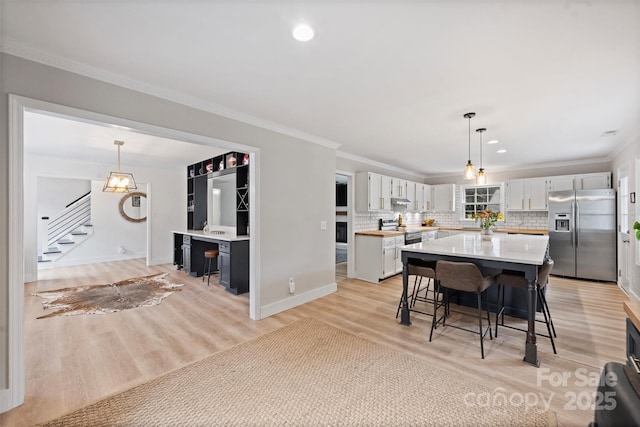 1119 Thornsby Ln, Matthews, NC 28105 - kitchen featuring appliances with stainless steel finishes, light countertops, a breakfast bar area, light wood finished floors, and tasteful backsplash