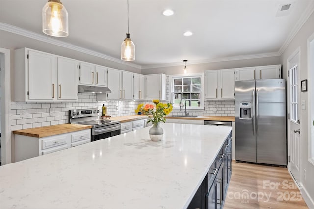 1119 Thornsby Ln, Matthews, NC 28105 - kitchen featuring appliances with stainless steel finishes, butcher block countertops, under cabinet range hood, a sink, and crown molding