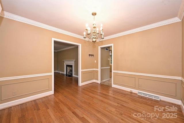 1961 Runnymede Ln, Charlotte, NC 28211 - empty room with a chandelier, crown molding, a decorative wall, wood finished floors, and a fireplace with flush hearth