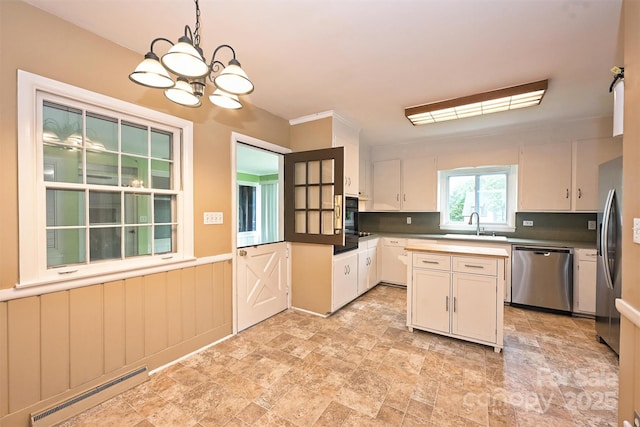 1961 Runnymede Ln, Charlotte, NC 28211 - kitchen with appliances with stainless steel finishes, a baseboard radiator, a chandelier, stone finish floors, and pendant lighting