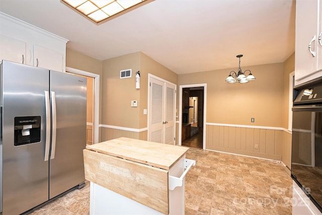 1961 Runnymede Ln, Charlotte, NC 28211 - kitchen featuring stainless steel refrigerator with ice dispenser, wainscoting, a chandelier, white cabinets, and black oven