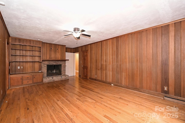 1961 Runnymede Ln, Charlotte, NC 28211 - unfurnished living room with a ceiling fan, wood walls, wood finished floors, and a brick fireplace
