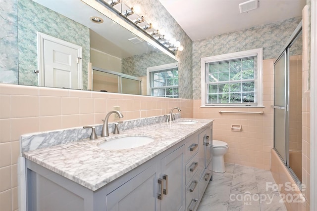 1961 Runnymede Ln, Charlotte, NC 28211 - bathroom with tile walls, double vanity, marble look tiles, toilet, and combined bath / shower with glass door