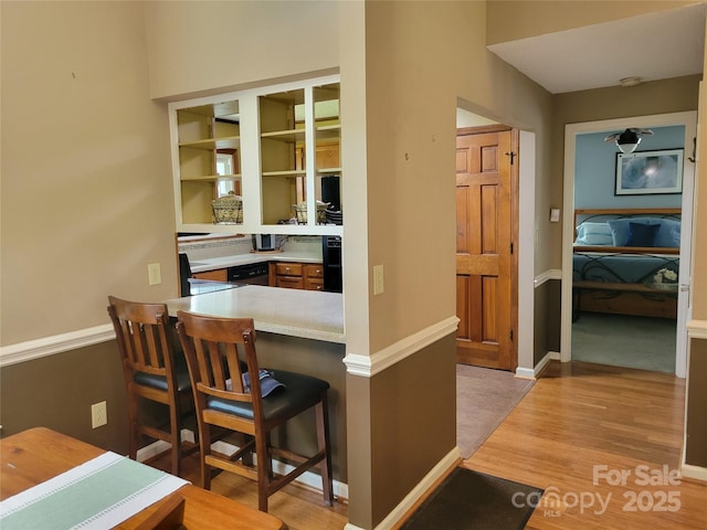 2777 Old S Ct NW, Concord, NC 28027 - kitchen featuring light wood-type flooring, a breakfast bar, a peninsula, light countertops, and stainless steel dishwasher