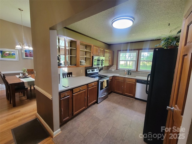 2777 Old S Ct NW, Concord, NC 28027 - kitchen with stainless steel appliances, a textured ceiling, light countertops, a chandelier, and brown cabinetry