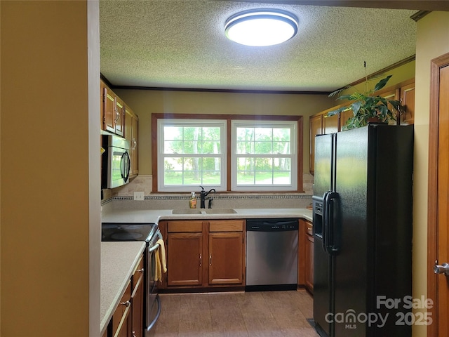2777 Old S Ct NW, Concord, NC 28027 - kitchen featuring stainless steel appliances, a textured ceiling, light countertops, brown cabinetry, and light wood-style floors