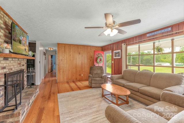 310 Yarbro Rd, Kings Mountain, NC 28086 - living area with a textured ceiling, a fireplace, a ceiling fan, wood finished floors, and wooden walls
