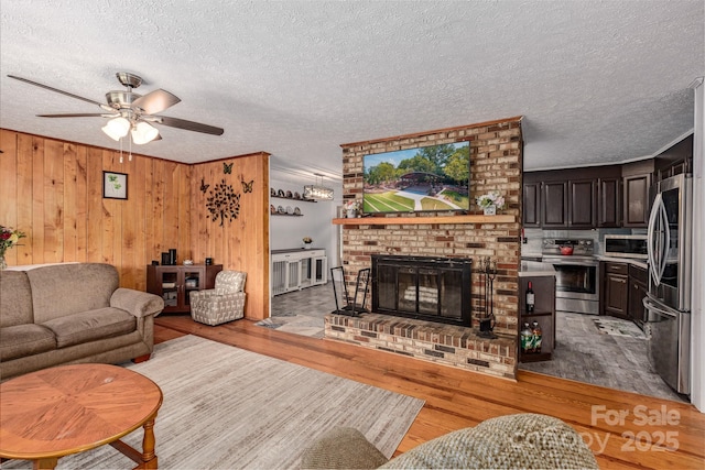 310 Yarbro Rd, Kings Mountain, NC 28086 - living area featuring light wood-type flooring, a ceiling fan, a fireplace, a textured ceiling, and wooden walls