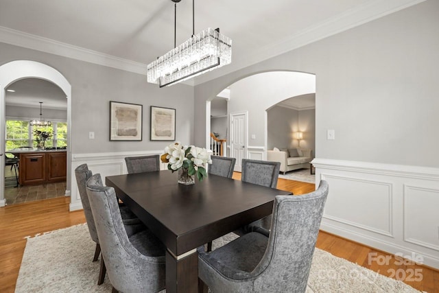 11139 Tradition View Dr, Charlotte, NC 28269 - dining space with crown molding, arched walkways, a chandelier, light wood-type flooring, and a wainscoted wall