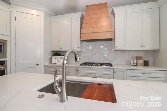 332 Canvasback Rd, Mooresville, NC 28117 - kitchen with custom exhaust hood, decorative backsplash, a sink, light stone counters, and crown molding