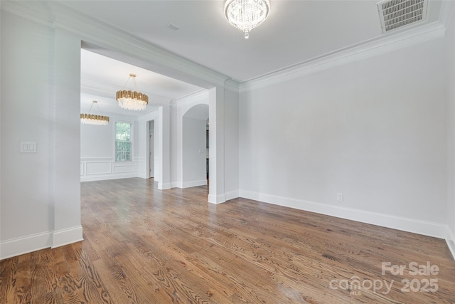 2785 Disney Pl, Indian Land, SC 29707 - spare room featuring a chandelier, ornamental molding, arched walkways, wood finished floors, and baseboards