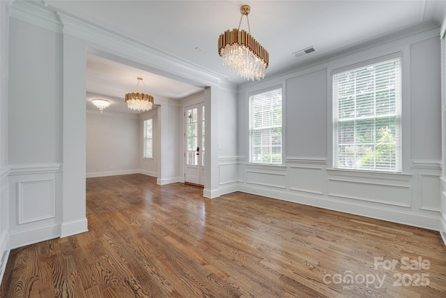 2785 Disney Pl, Indian Land, SC 29707 - unfurnished dining area with a chandelier, ornamental molding, healthy amount of natural light, wood finished floors, and a wainscoted wall