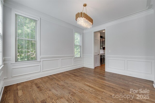 2785 Disney Pl, Indian Land, SC 29707 - unfurnished dining area with a chandelier, crown molding, a wainscoted wall, wood finished floors, and a decorative wall