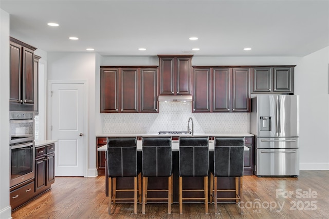 2785 Disney Pl, Indian Land, SC 29707 - kitchen with stainless steel appliances, light wood finished floors, light countertops, tasteful backsplash, and a breakfast bar area