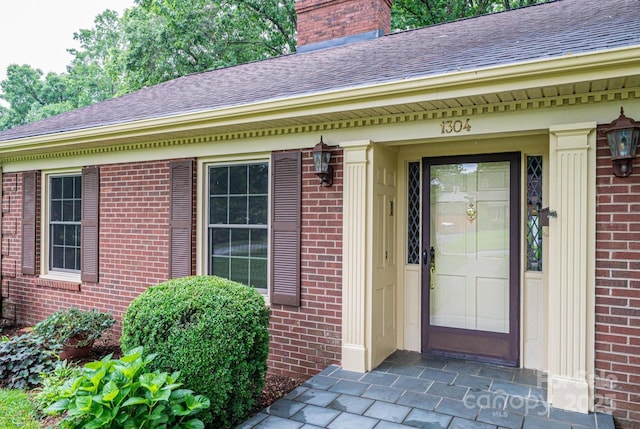 1304 5th Street Cir NW, Hickory, NC 28601 - view of exterior entry with roof with shingles, brick siding, and a chimney