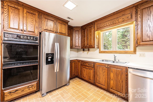 1304 5th Street Cir NW, Hickory, NC 28601 - kitchen featuring stainless steel appliances, a sink, brown cabinets, and brick patterned flooring