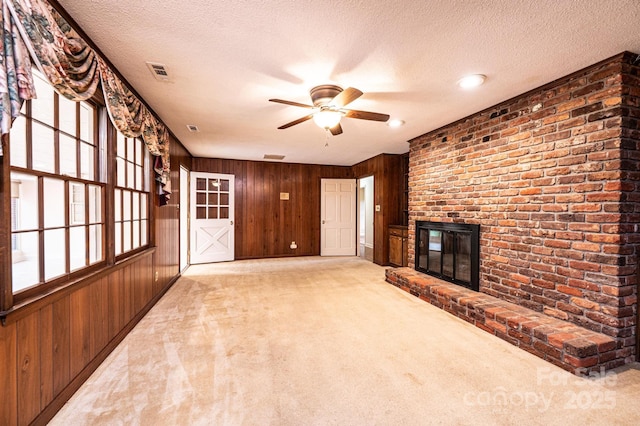 1304 5th Street Cir NW, Hickory, NC 28601 - unfurnished living room featuring wood walls, ceiling fan, a textured ceiling, a brick fireplace, and carpet floors