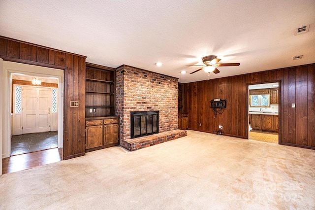 1304 5th Street Cir NW, Hickory, NC 28601 - unfurnished living room with wood walls, a ceiling fan, a fireplace, and light colored carpet