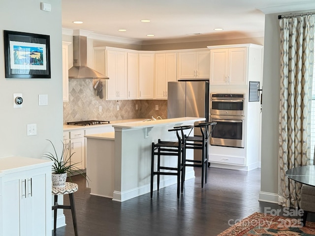 114 Mint Ave Unit A, Mooresville, NC 28117 - kitchen featuring wall chimney exhaust hood, appliances with stainless steel finishes, dark wood-type flooring, a kitchen breakfast bar, and decorative backsplash