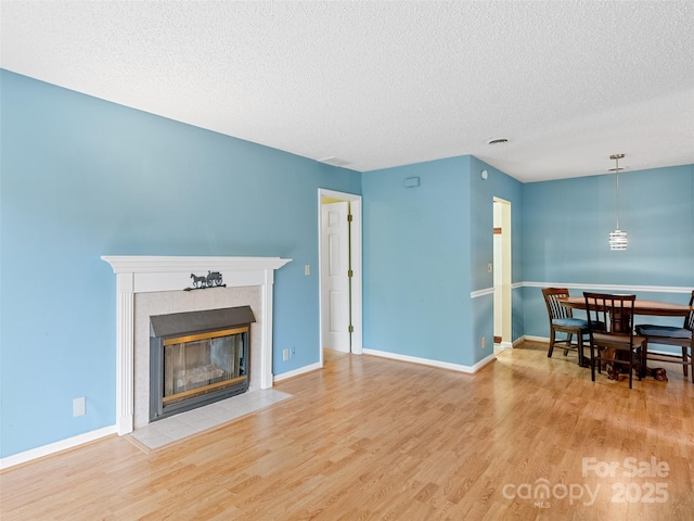 110 Heywood Rd Unit 17C, Arden, NC 28704 - living room featuring a textured ceiling, wood finished floors, a tiled fireplace, and baseboards